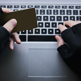 A Person Holding a Card and Using a Laptop