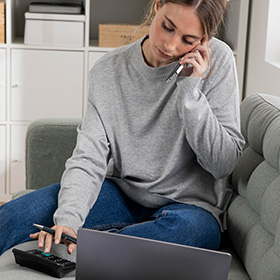 A Woman Using a Calculator and Speaking Over the Phone